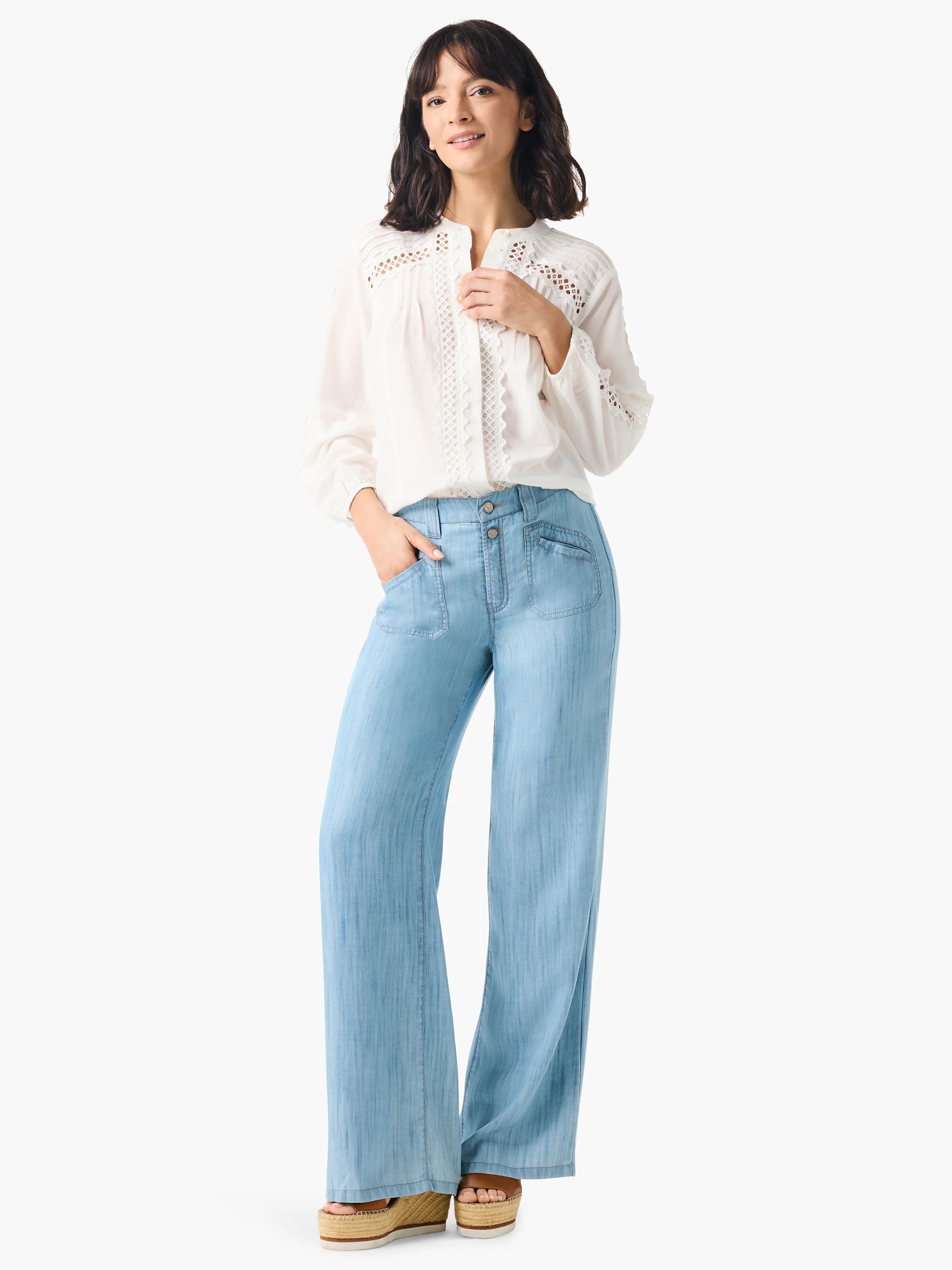 White long-sleeve blouse with eyelet detail; light blue wide-leg jeans.