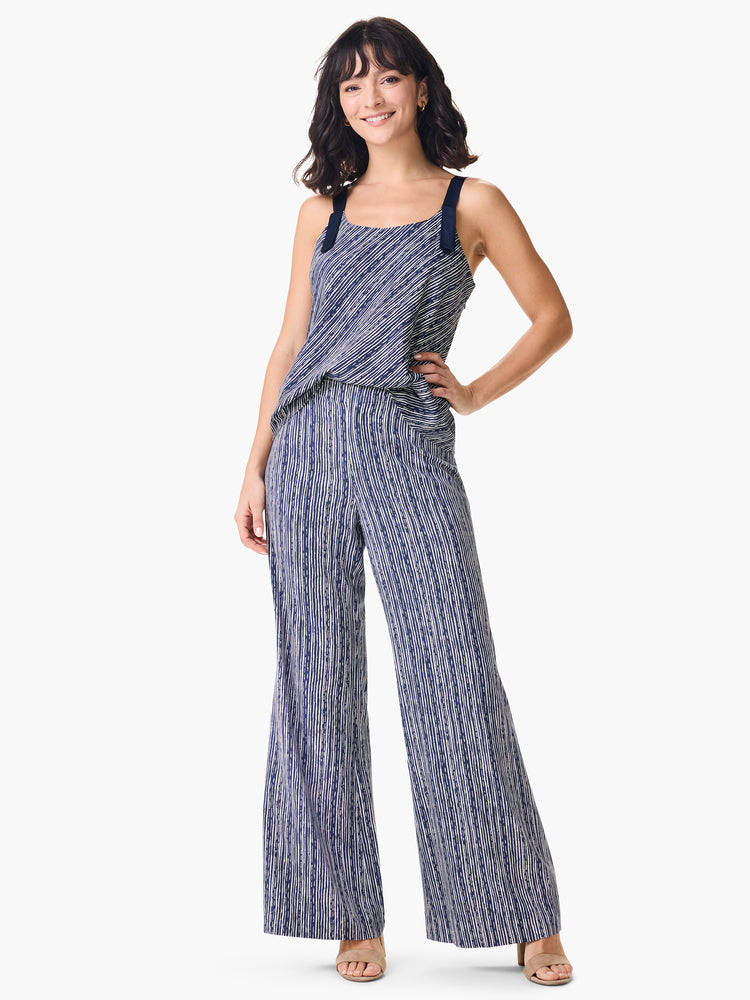 Flowing navy striped jumpsuit with a blouson bodice, wide trouser legs, and dark contrast straps tied on the shoulders.