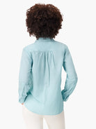 Back view of a light blue long-sleeved shirt with back pleats and a rounded hem.