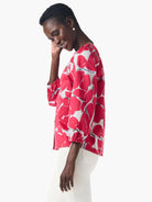 Pink shirt with an abstract, bold floral print in grey and white.  Three-quarter sleeves.