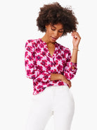 Pink top with a V-neck and long sleeves. Features a pink and purple abstract floral print.