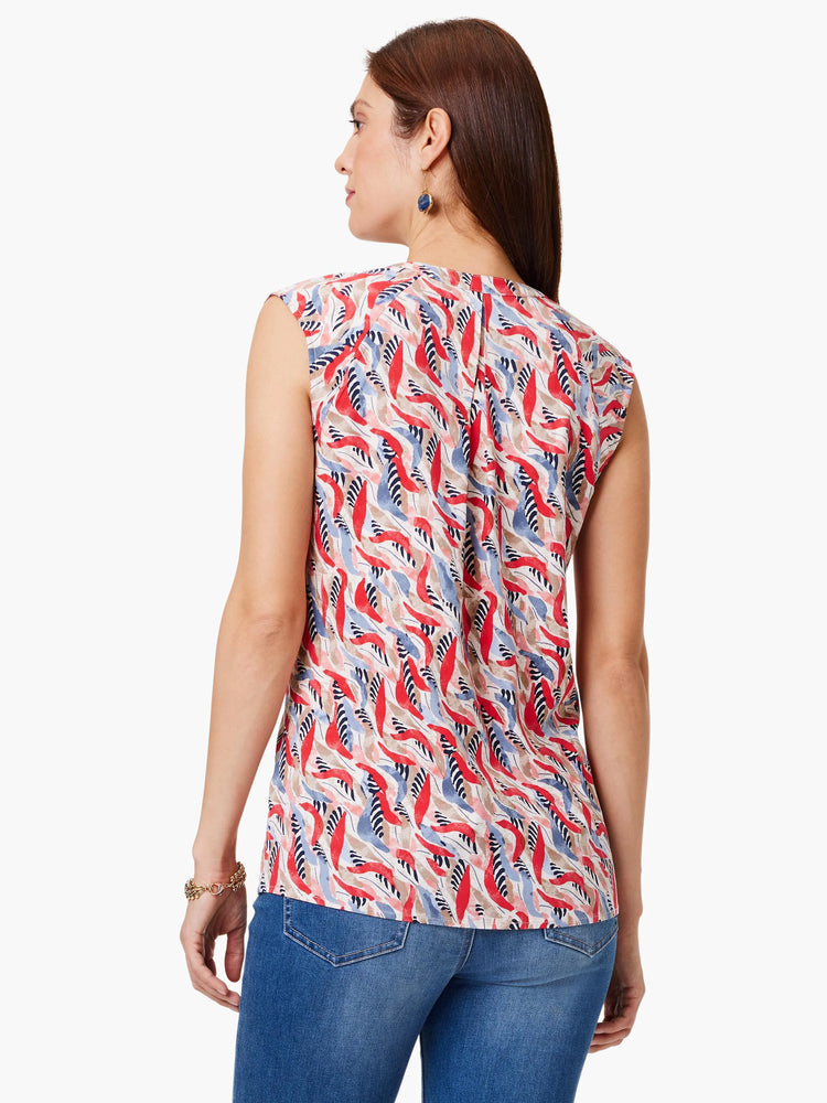 Sleeveless, cream top with red, blue, and black abstract leaf print. V-neck back.
