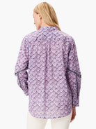 Lavender shirt with a repeating dark purple floral pattern.  Long sleeves feature a lace trim.  Button front (unbuttoned).