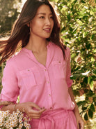 Pink button-down shirt; three-quarter sleeves, two chest pockets, gold buttons.  Model shown wearing matching pink pants.