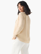 Beige, long-sleeve shirt; collared, button-down; drapey fabric.  Model shown wearing with white pants.