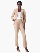 Beige straight-leg pants with thin, vertical pink and green stripes; model is wearing them with a matching blazer.