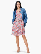 A knee-length shirt dress with a belted waist.  The print features red, blue, and beige abstract shapes on a cream...