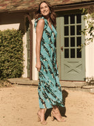 Teal maxi dress with dark green & beige leaf print. Sleeveless, tiered skirt, ruffle neckline.