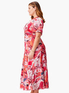 Red, pink, and white abstract floral midi dress with short sleeves and tiered skirt.