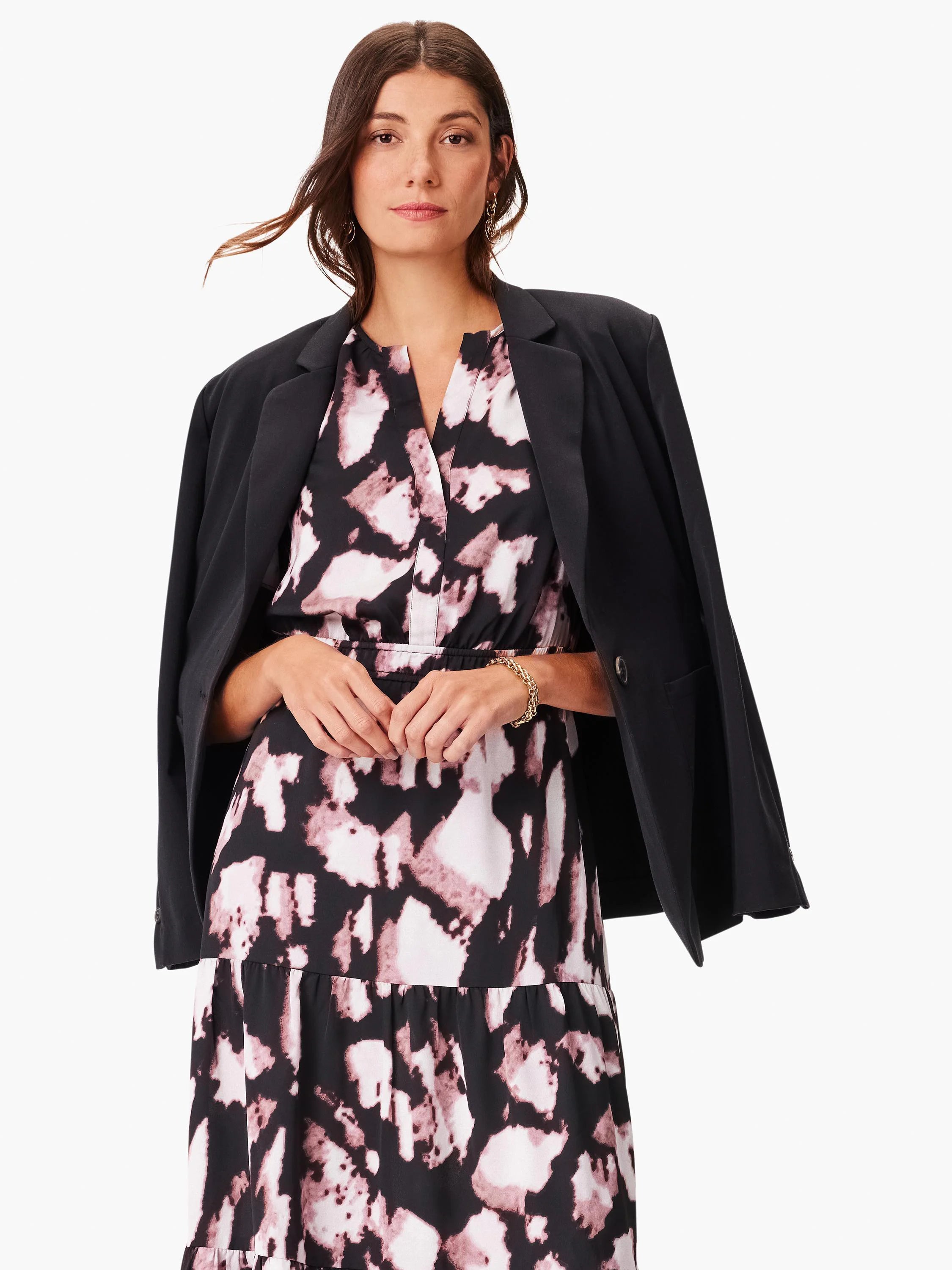 Midi dress with black background and mauve/pink abstract print.  Features a tiered skirt and V-neck. Model wears a black...