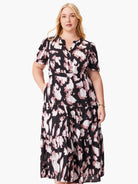 Midi dress, black background with mauve and white abstract print. Short sleeves, V-neck, tiered skirt, and pockets.