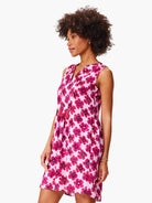 Pink sleeveless dress with a V-neck and dark pink floral print.  Features small coral tassels at the neckline.