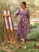 Pink and gray floral midi dress with puff sleeves and a smocked bodice.  Features a ruffled hem.