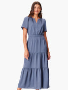 Full-length dusty blue dress with V-neck, short sleeves, elastic waist, and tiered maxi skirt.