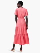 Coral pink midi dress with short puff sleeves, smocked waist, and tiered skirt, shown from the back.