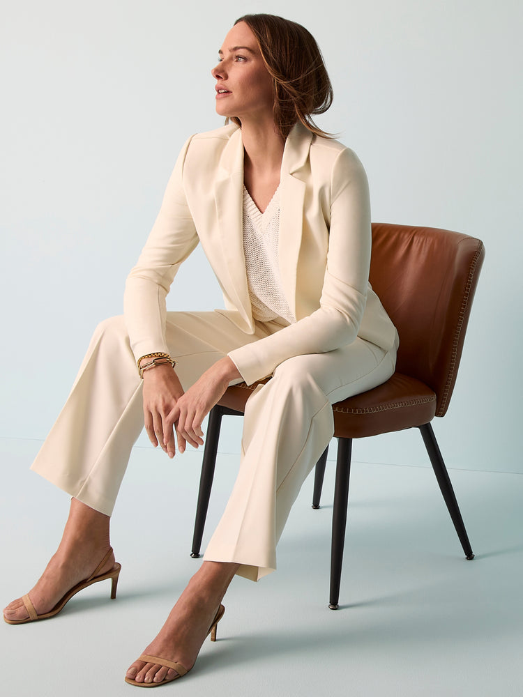A tailored cream suit features a fitted blazer and modern, slightly cropped wide-leg trousers for a refined look.