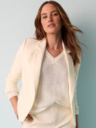 Elegant cream tailored blazer with notched lapels worn over a textured knit top, creating a chic monochromatic look.