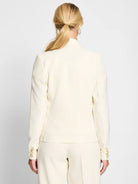 Back view of a cream tailored blazer with three light brown buttons on each cuff.