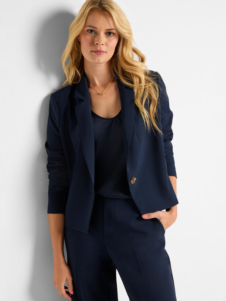 This navy blue, open-front, cropped blazer has structured lapels, three-quarter sleeves, and a single decorative button.