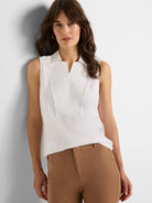 White sleeveless tank with a pointed collar, V-neck, and structured vertical panels on the front.
