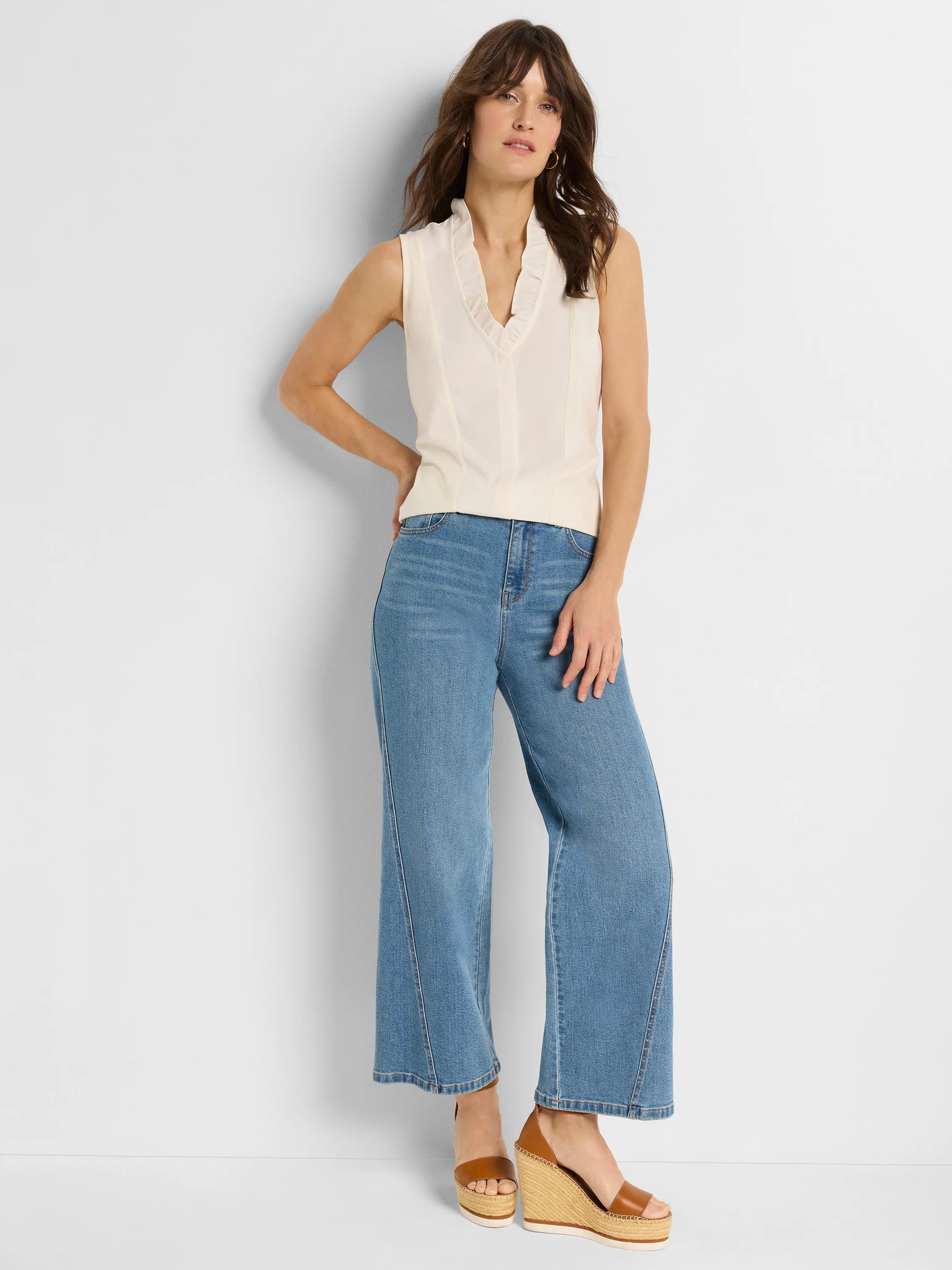 Cream sleeveless tank with a ruffled V-neckline and subtle front seams.