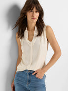 Cream sleeveless tank with ruffled V-neck and partial button front.