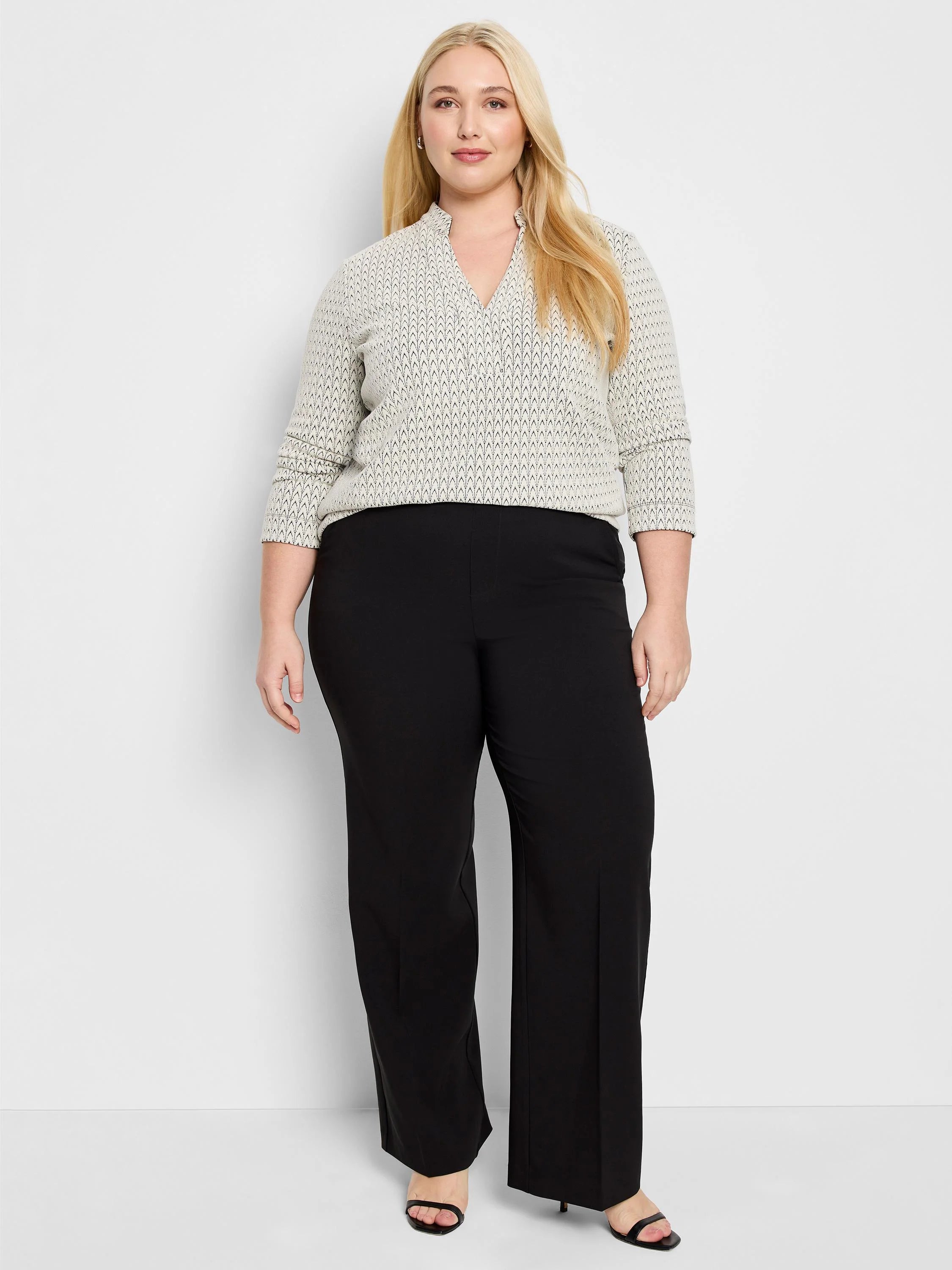 Cream knit V-neck top with long sleeves and a dark subtle swirling pattern.