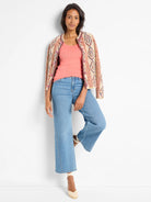 A model wears a coral, ribbed knit scoop neck tank. It features a fitted silhouette.