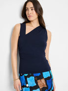 Navy tank top with asymmetrical angular neckline, one wide shoulder strap, and subtle left side ruching.