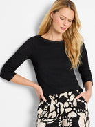 Black bubble knit top with long sleeves and a wide, smooth-trimmed neckline.