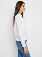 White eyelet long-sleeve top with floral perforations and a split neck.