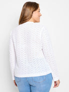 White knit top with long sleeves and all-over eyelet floral cutouts, shown from the back.