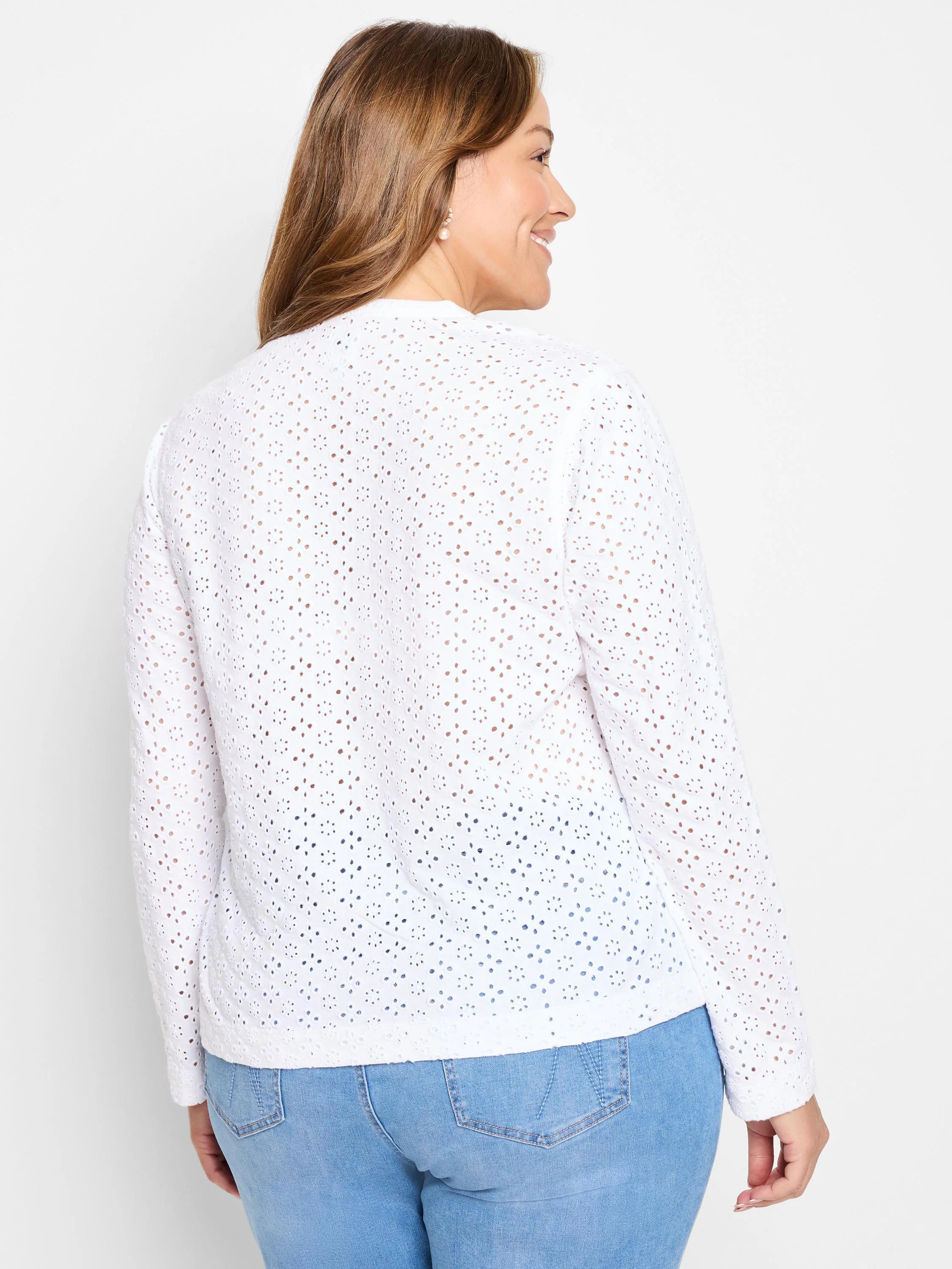 White knit top with long sleeves and all-over eyelet floral cutouts, shown from the back.