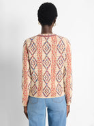 Back of a cream knit jacket with multicolored woven diamond patterns.