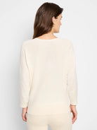 Model from back in a cream, long-sleeved sweater with ribbed cuffs and hem.