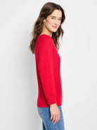 Red long-sleeved V-neck sweater with fine knit and ribbed cuffs, modeled on a woman.