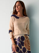 Beige sweater with dark blue abstract pattern accents.  Long sleeves, round neck. Knitted texture with cut-out detailing.
