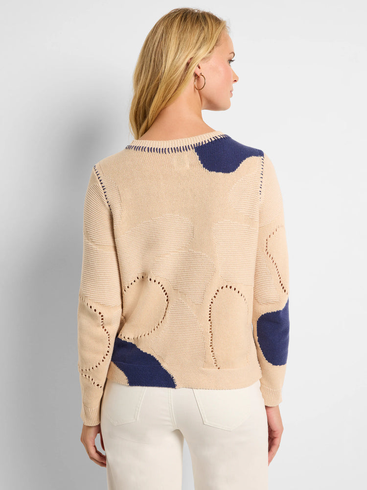 Beige knit sweater with navy pebble-like patches and circular perforations.