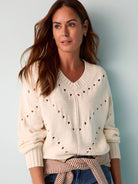 Off-white pointelle knit v-neck sweater with  long sleeves and subtle pattern.