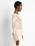 Cream sweater with small, scattered multi-colored flecks and an open-knit, textured weave.