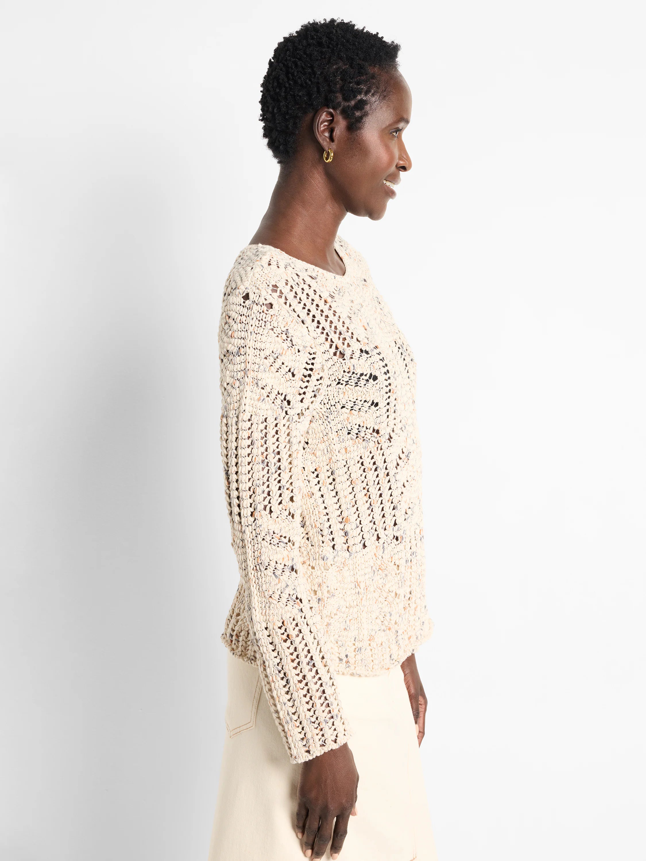 Cream sweater with small, scattered multi-colored flecks and an open-knit, textured weave.