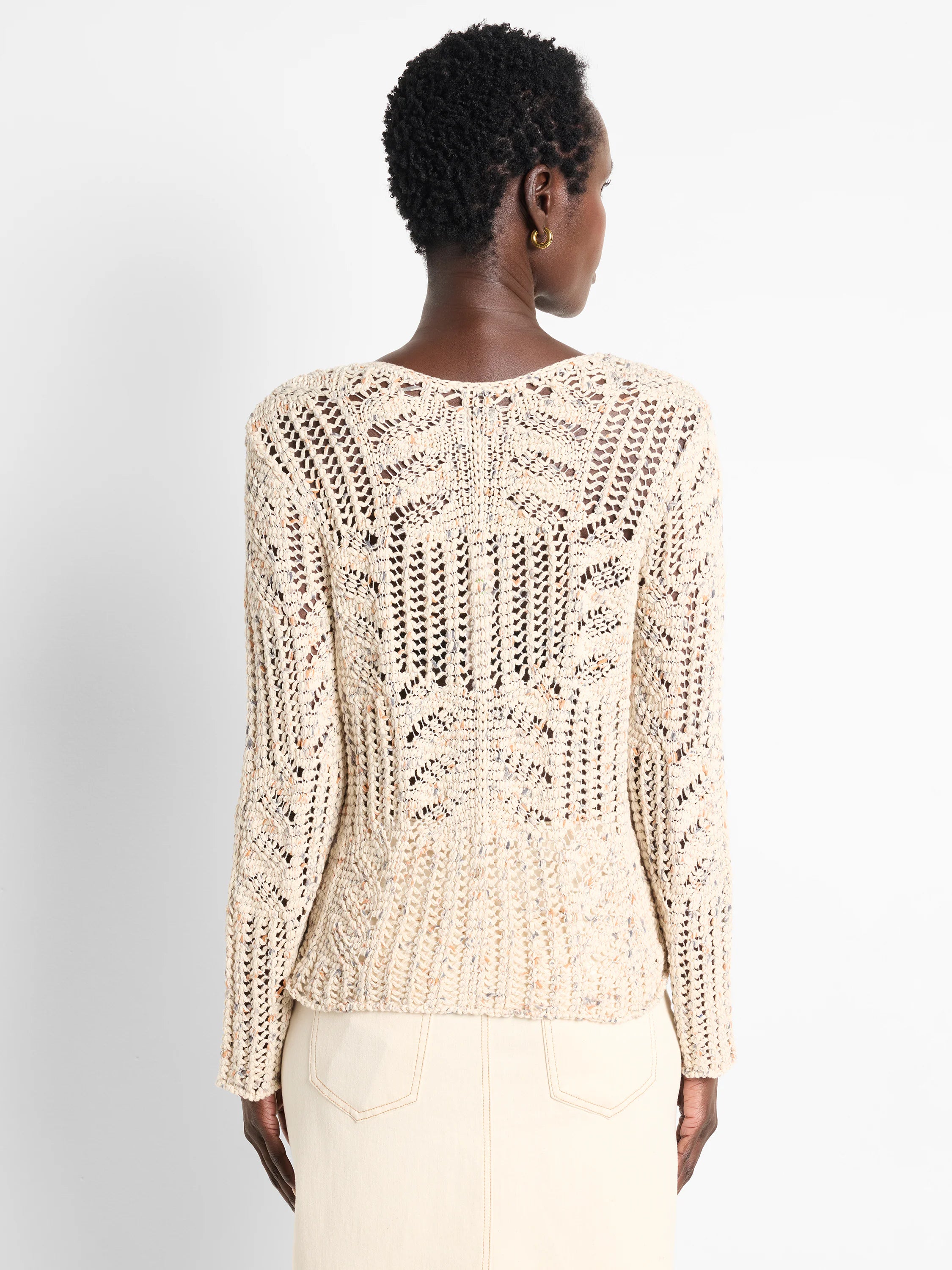 Cream open-knit sweater with tiny blue & orange speckles, forming a geometric pattern. Model shown from behind.