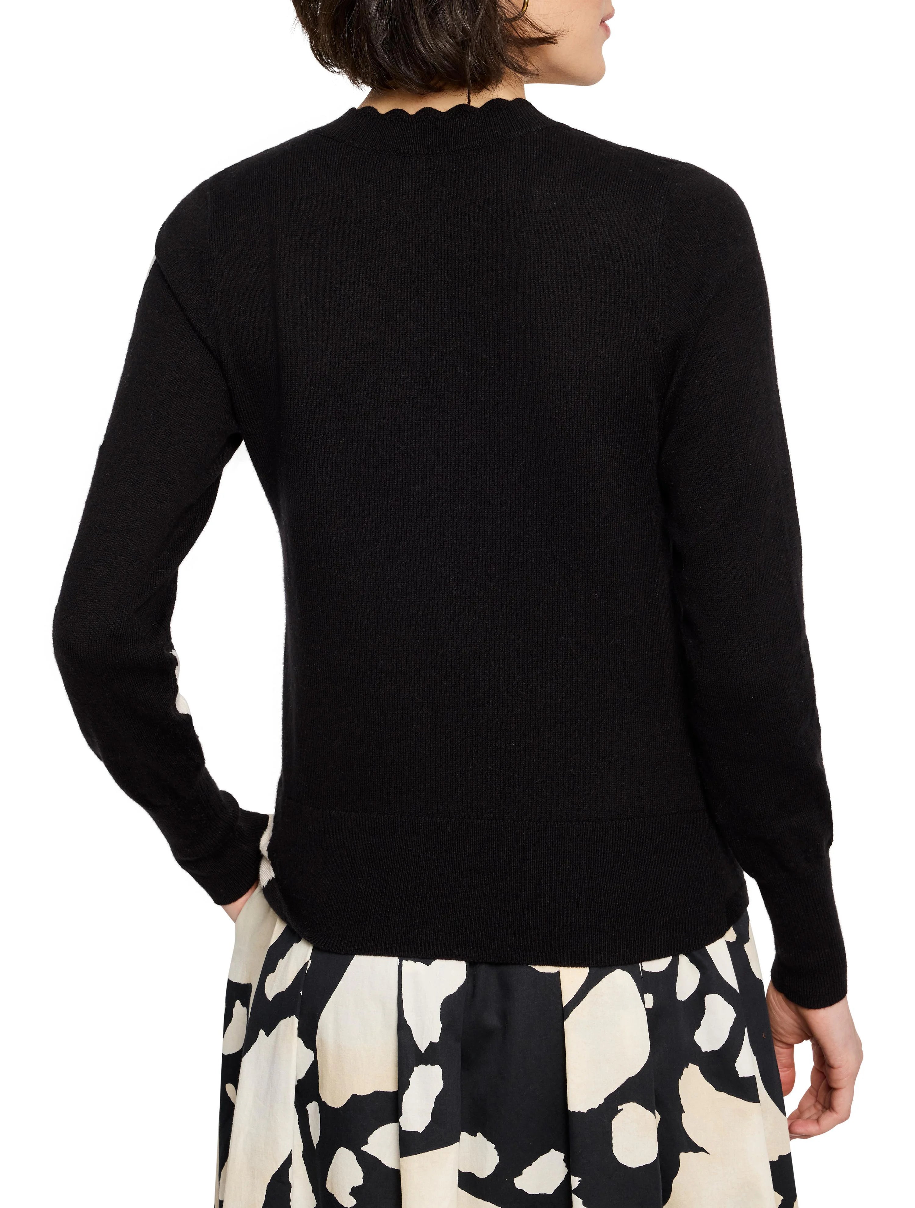 Black long-sleeved sweater, scalloped neckline.