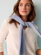 Off-white V-neck sweater with a light blue knitted detail draped around the neck.  Open knit texture.