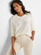 Off-white, V-neck, long-sleeve, loosely knit sweater.