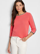 Coral ribbed sweater; neckline, sleeves edged in black & white stitching.  Three-quarter sleeves.