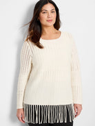 Off-white, textured knit sweater with fringe hem and long sleeves.
