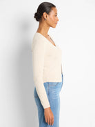 Off-white ribbed V-neck cardigan with long sleeves. It has a cropped length and is worn open.