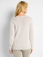 Light beige knit sweater, back view. Features a rounded neck, long sleeves, and ribbed cuffs and hem.
