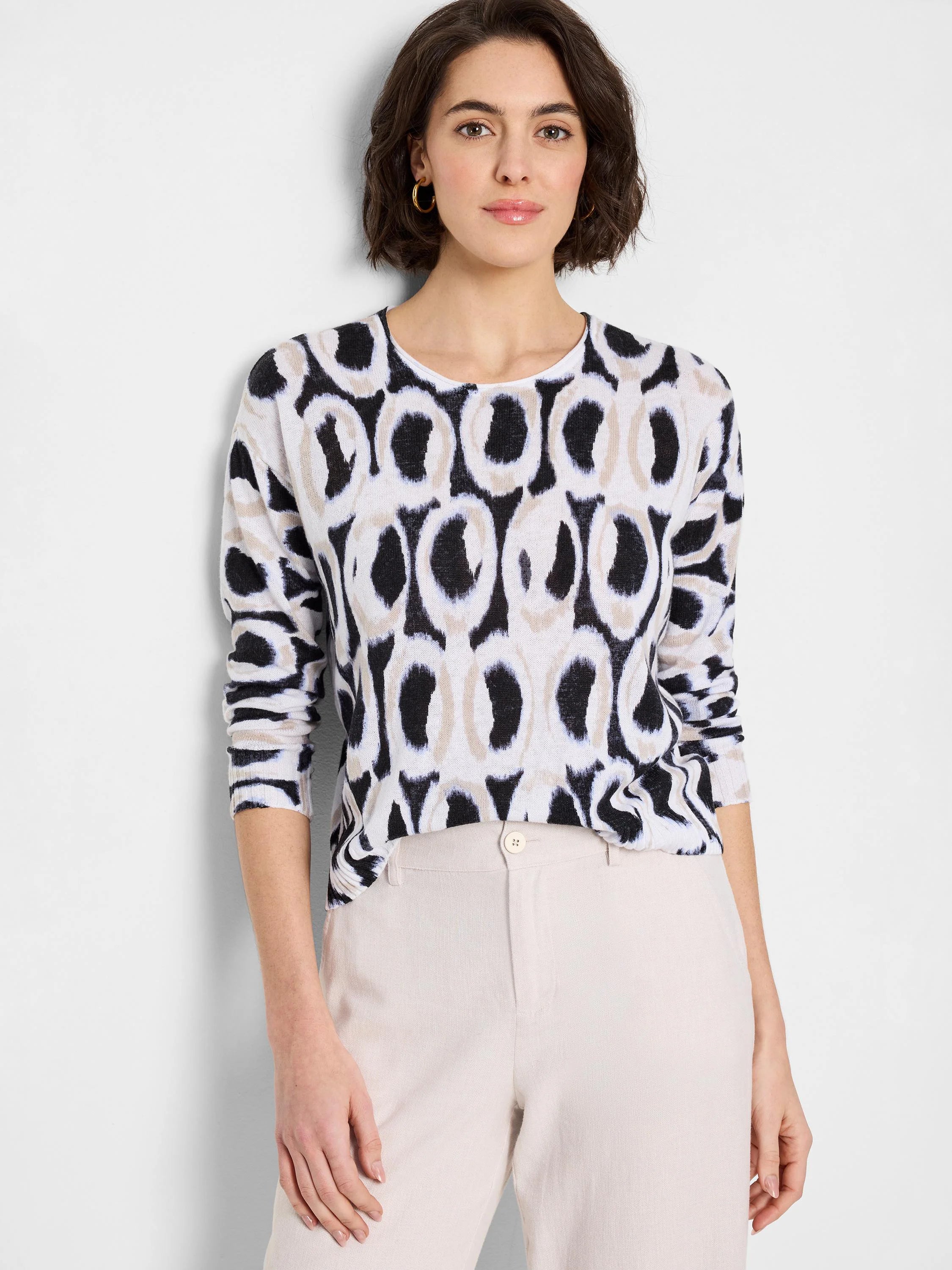 White long-sleeve crewneck sweater with black and beige ikat-style circular pattern.
